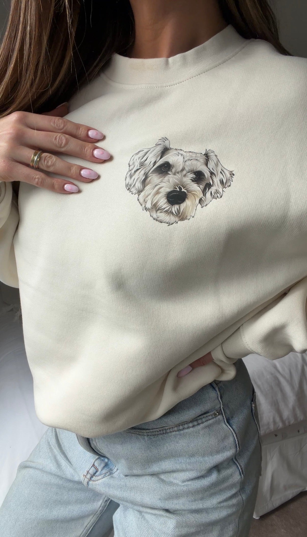 Person wearing a beige sweatshirt with a dog illustration on a neutral background